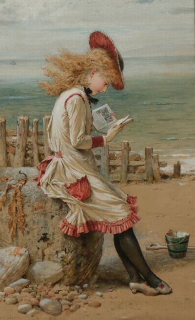 A young girl in a dress reading by the seaside on a cloudy day.